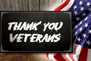 Thank you Veterans on a chalkboard sign in front of barn boards and an American flag Thank you Veterans on a chalkboard sign in front of barn boards and an American flag